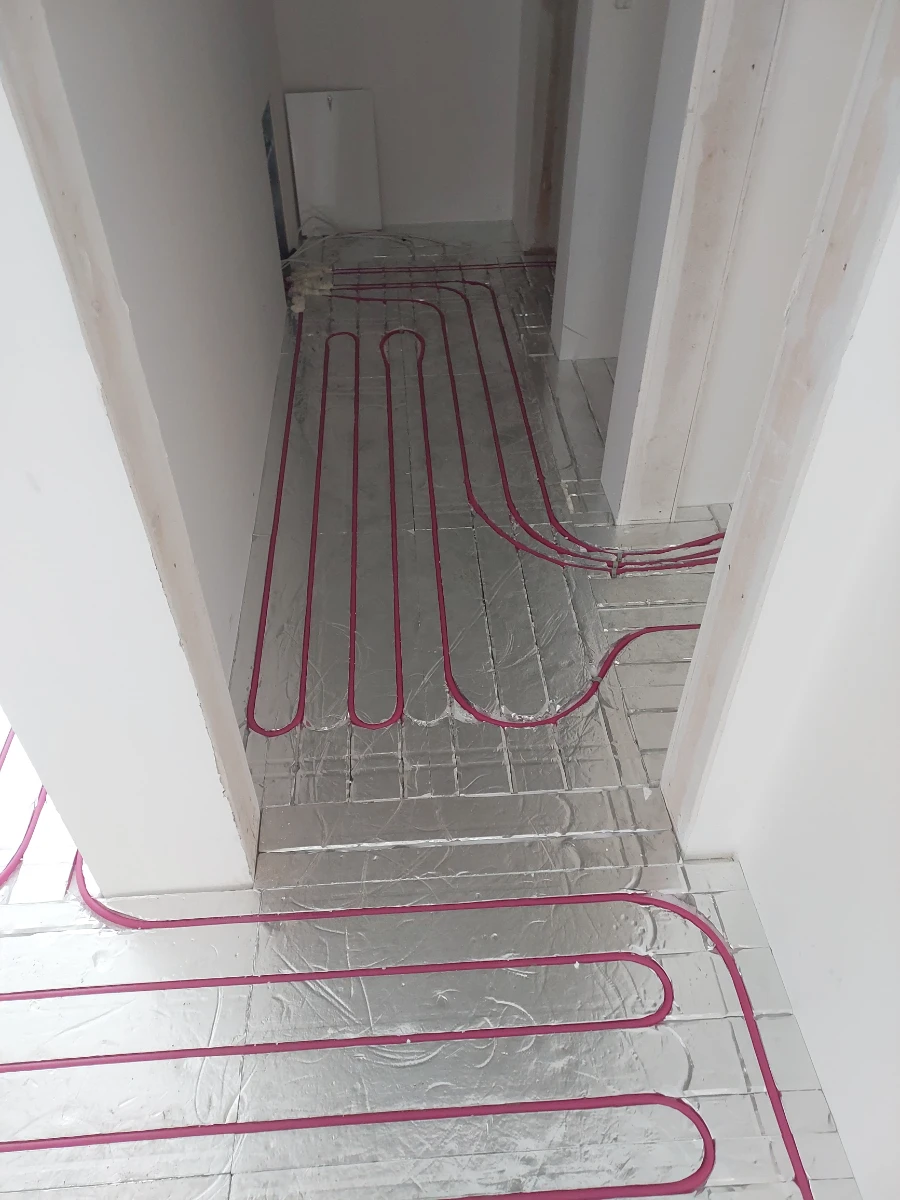 Montaż rur ogrzewania podłogowego wodnego na podkładzie izolacyjnym przed wykonaniem wylewki