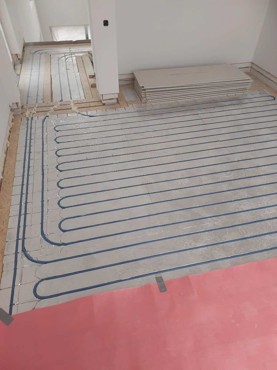 Spiralnie ułożone niebieskie rury ogrzewania podłogowego wodnego na izolacji z folii termoizolacyjnej