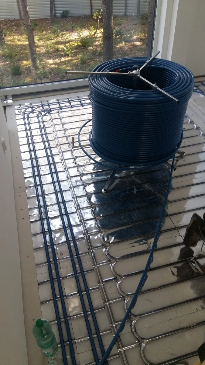 Rozłożone rury ogrzewania podłogowego wodnego na podłożu izolacyjnym z dużą rolką przewodów